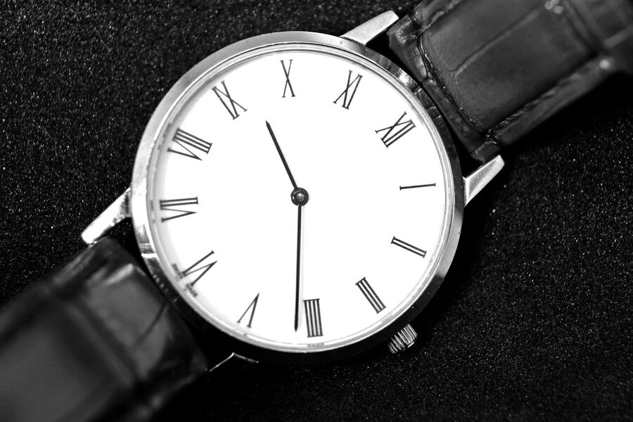 Gros plan sur le cadran et le verre d'une montre habillée à bracelet cuir, angle de prise de vue montrant les reflets et l'état de surface de la glace