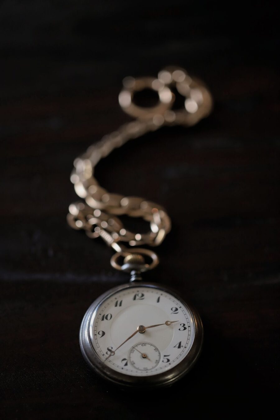 Montre de gousset ancienne à chaîne sur fond sombre — estimation et restauration de montres de famille en atelier
