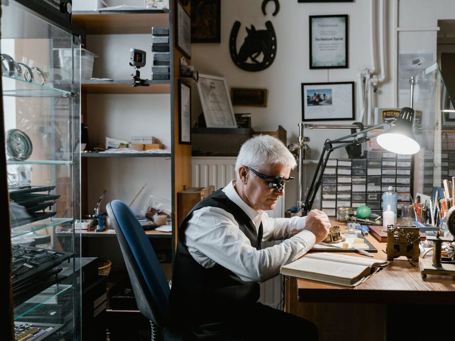 Horloger au travail dans son atelier avec loupe binoculaire — restauration de montres françaises Herbelin, LIP et Kelton