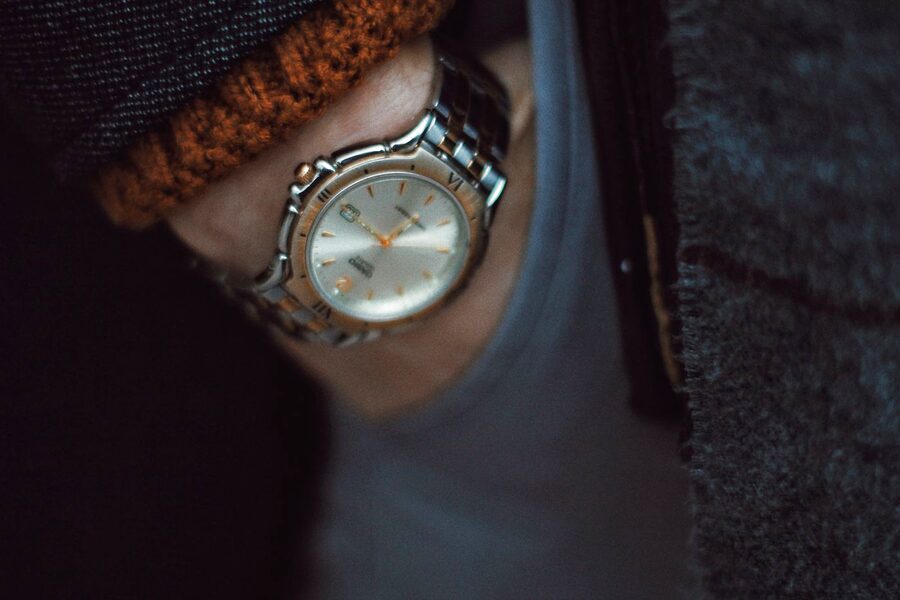 Montre en acier à bracelet métallique portée au poignet sous une manche de pull, en lumière douce