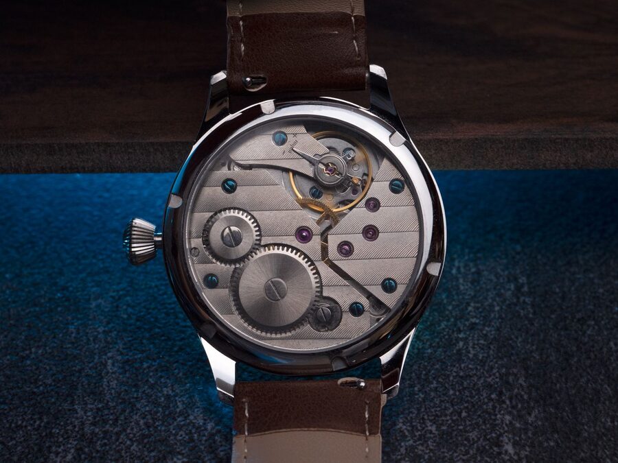 Montre mécanique à remontage manuel vue par son fond transparent, laissant voir les barillets, le rouage et le balancier sans masse oscillante