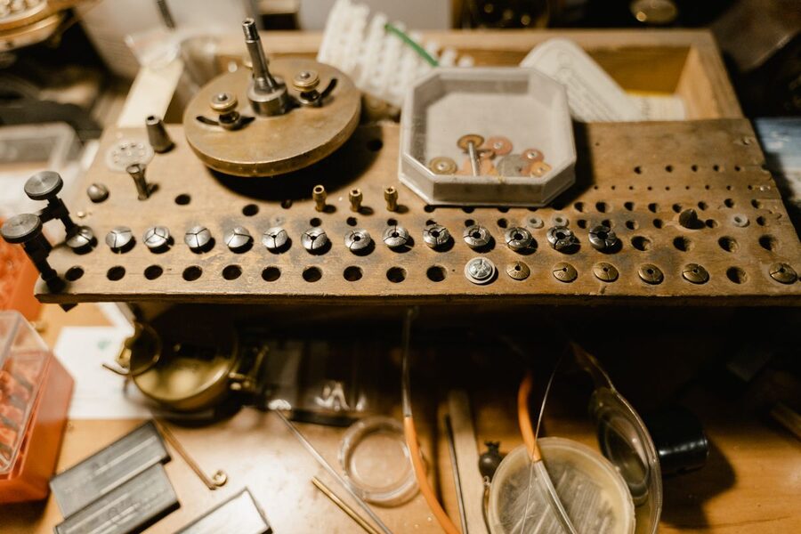 Outillage d'horloger sur un établi d'atelier : pinces de tour, jeux de pièces et instruments de précision