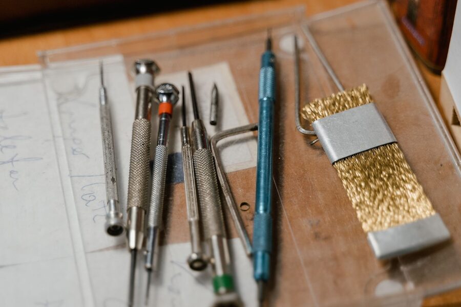 Outils d'horloger de précision posés sur un établi, tournevis, chasse-goupilles et brosse laiton utilisés pour le remplacement des bracelets et des barrettes à ressort
