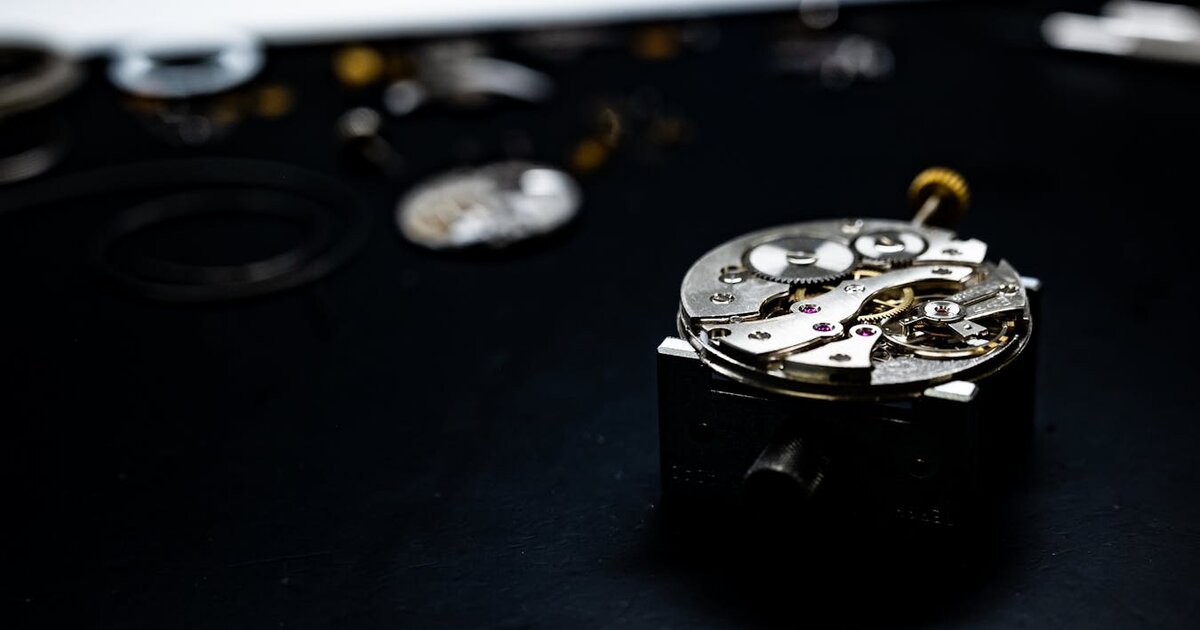 Horloger diagnostiquant une montre dont la pile ne tient pas — close-up mécanisme