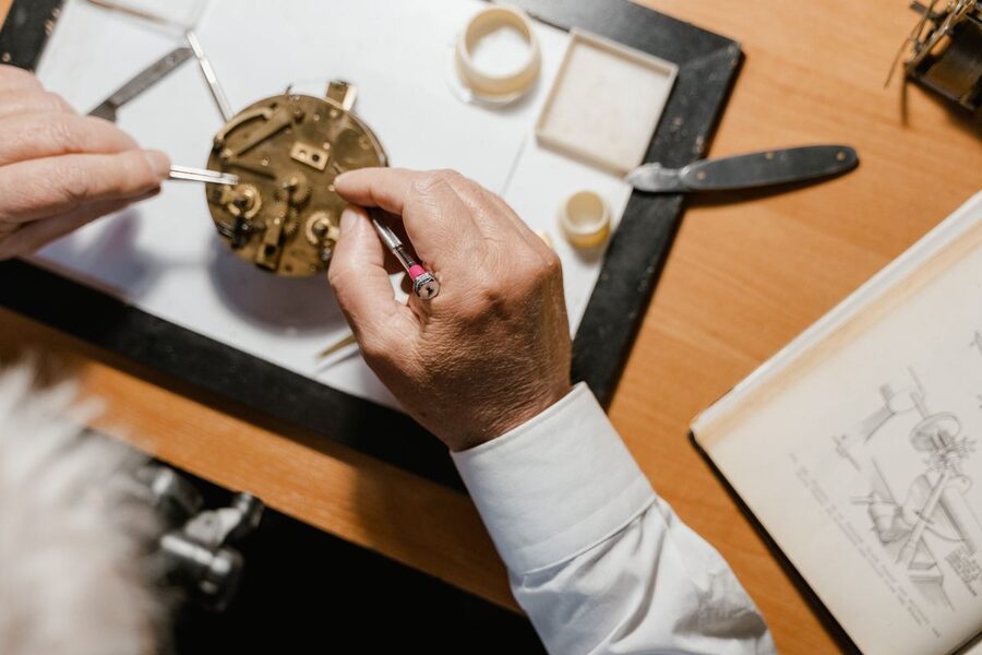Horloger réglant un mouvement mécanique à la brucelles sur son établi — révision de montre Herbelin en atelier spécialisé