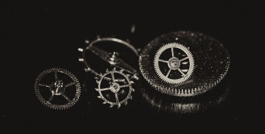 Rouages et roues dentées de mouvement de montre mécanique posés sur fond noir, pièces détachées d'horlogerie de différents diamètres prêtes pour un remontage en atelier